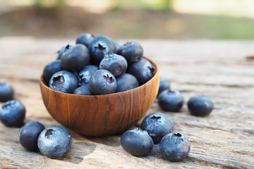 Fresh blueberries in wooden bowls on old wooden table background