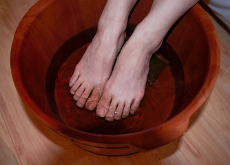 A woman soaks her feet in a deep reddish brown foot bath