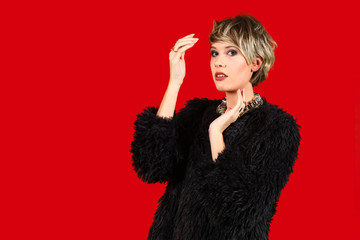 young female model with short hair posing in front of red background