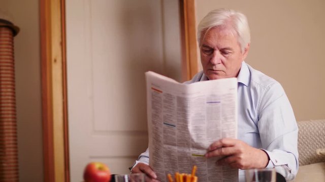 Modern senior man reading newspaper