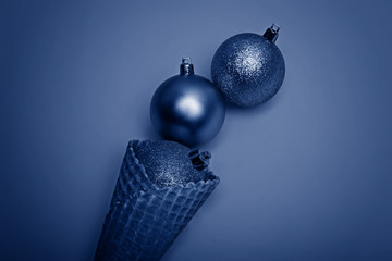 Color of the year 2020: Blue. Golden christmas balls in ice cream waffle cone.