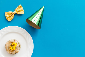 Birthday party for pets concept. Pet feed with festive candle and parry hat on blue background top-down copy space