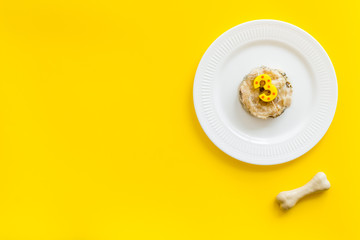 Birthday party for puppy concept. Dog feed, candle in shape of number three, bones on yellow background top-down copy space