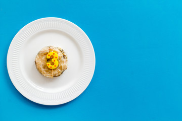 Birthday party for pets concept. Pet feed with festive candle in shape of three on blue background top-down copy space