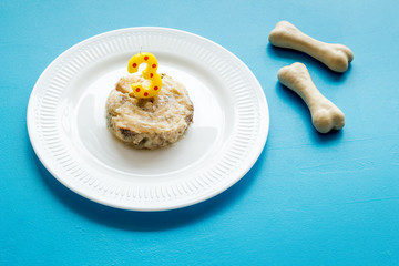 Birthday treat for puppy concept. Dog feed, candle in shape of number three, bones on blue background