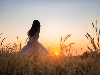 Naklejka premium Trendy girl in stylish summer dress feeling free in the field with flowers in sunshine.