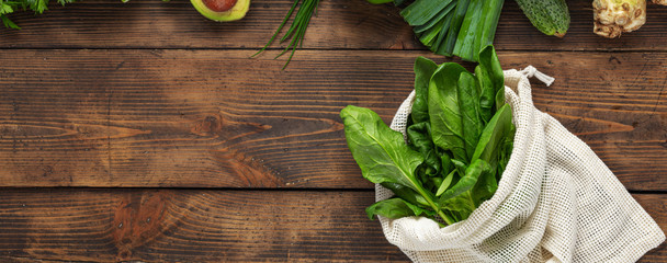 Shopping bag with green vegetable on wooden background top view. Healthy food clean eating. Copy space. Purchase healthy food