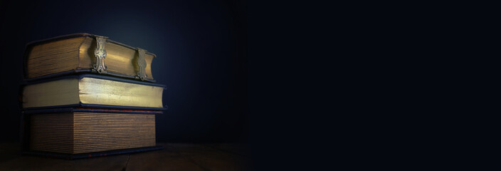 stack of antique books on old wooden table. fantasy medieval period and religious concept.