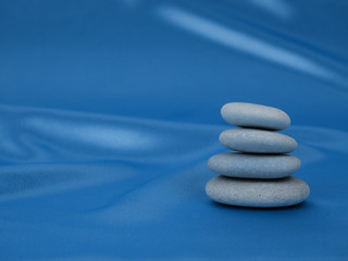Fototapeta na wymiar Stack of Zen stones on abstract blue classic color background of garlands. Relax still Life with folded stones. Zen pebbles, stones, Spa-calm scenes slow life the soul of the imperturbable tranquility