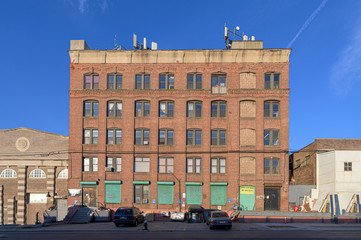 Old-fashioned brickwall factory building against a blue sky on a beautiful sunny day in the Bronx,...