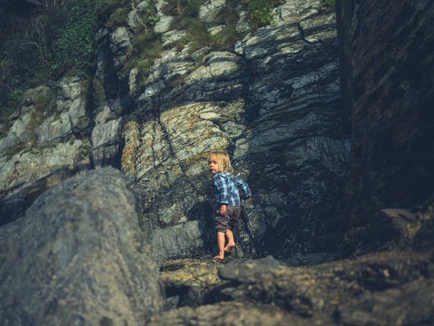 Little toddler by rocks on the coast