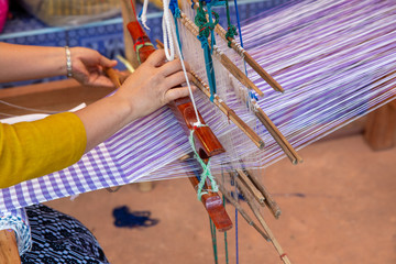 Cotton weaving. Woman hand weaving cotton on manual loom. Thai cotton handmade. Homespun fabric process. The process of fabric weaving in vintage weaver machine. Selective focus.