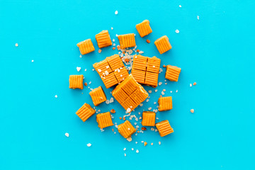 Salted caramel pieces - paradoxical sweets - on blue background top view frame