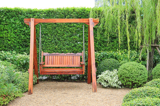 Wooden swing chair in natural green garden. Beautiful garden furniture.