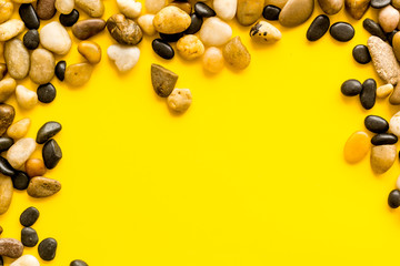 Summer trip to sea concept. Stones on yellow background top-down frame copy space
