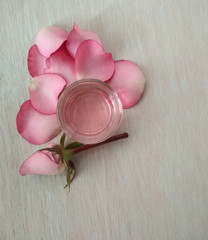 Rose  water, essential oil , with  pink flower and  petals on light turquoise wooden background, cosmetic, SPA, aromatherapy cosmetic concept