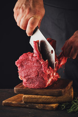 Male butcher cuts raw beef meat.