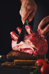 Male butcher cuts raw beef meat.