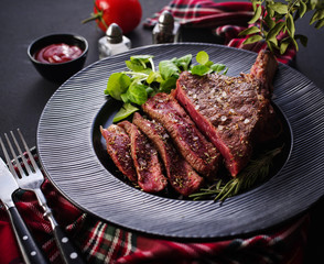 Steak on the bone. Rib eye. Tomahawk steak on the black plate with rosemary. Roasting - Rare. Entrecote