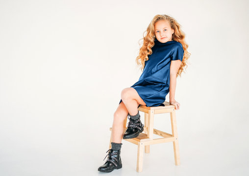 Beauty fashion portrait of smiling curly hair tween girl in blue leather dress and on white background