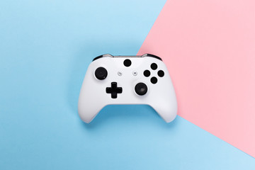 White joystick gamepad, game console on pink and blue background. Computer gaming technology play...