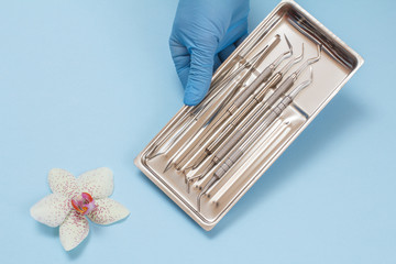 Dentist's hand with set of metal dental instruments for teeth dental care