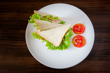 Sandwiches put on a white plate on a wooden table.