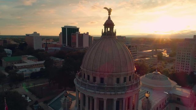 Aerial shot encircling the eagle on at the back of the Mississippi State Capitol buidling in Jackson Mississippi at sunset to reveal downtown behind