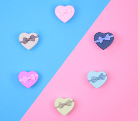 small multicolored gift boxes hearts on blue and pink background, top view, copy spase