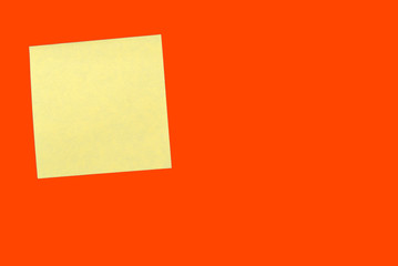 Yellow sticker note on a bright orange red. Business background, copy space
