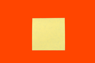 Yellow sticker note on a bright orange red. Business background, copy space