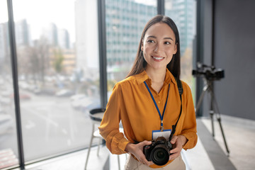 Dark-haired young cute reporter holding a camera