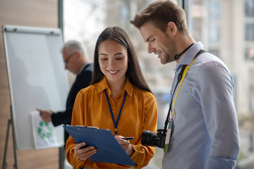 Female dark-haired reporter showing notes to her colleague