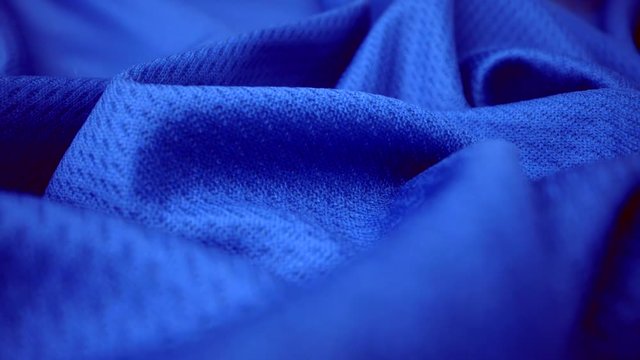 Close up detailed cloth texture of shiny spandex lycra cloth flowing with dolly shot in macro close-up view. Wavy clean elastic weave material. Textile abstract background. Clothing industry concept.