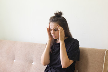 Sick young woman sitting at home with severe headache