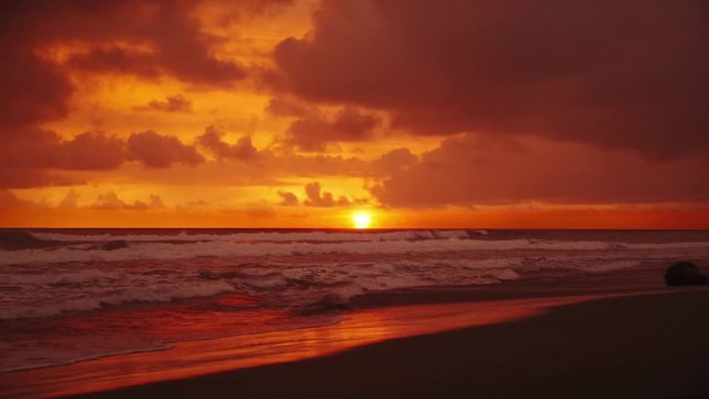 Beautiful Cinemagraph / seamless video loop time-lapse of a sunset at a wide and remote sandy Pacific beach near Manuel Antonio National Park, Costa Rica. The clouds are colorizing the entire sky red.