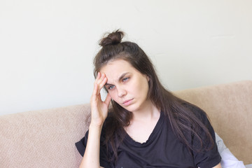 Sick young woman sitting at home with severe headache