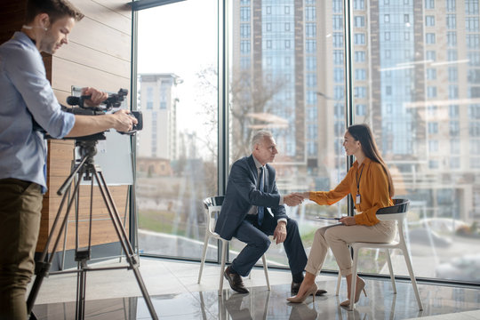 Team of reporters working on a interview with a grey-haired man