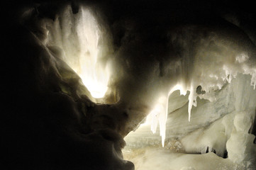 Inside the cave. Lighted section of the wall in the cave. Stalactites, stalagmites and ice growths inside the cave.