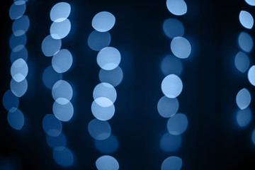 Delicate blue glitter bokeh lights on dark background.