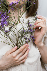 Fototapeta premium Faceless portrait of woman holding purple flowers in her hands, shallow selective focus