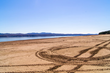 Beach. ATV tracks in the sand. Sky