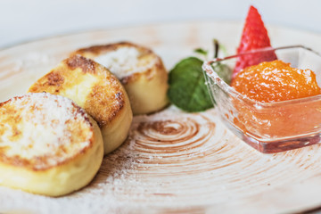 Cheesecakes with jam and strawberries in a plate. Breakfast.