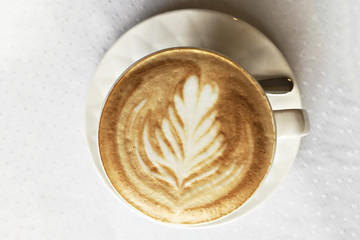 Cup with cappuccino coffee, on the surface of which a beautiful pattern of milk. Top view.