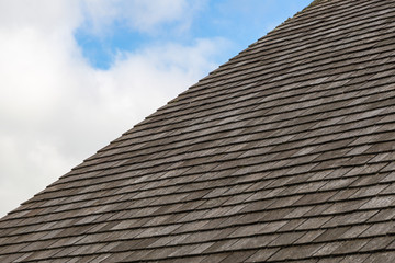 Grey slate roof with cloudy blue sky background