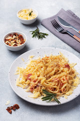 Pasta spaghetti with bacon egg cheese on a plate with spices. Traditional Italian dish Carbonara. Grey concrete table