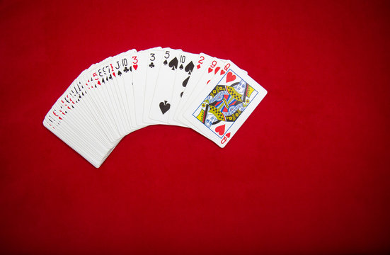 Deck of playing cards on red color velvet background. Top view with copy space.