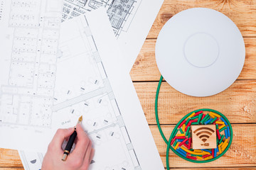 Engineering process. Man developing a network diagram for wifi access in cafe. Access point, floor layout, laptop and man hand on the bright background. Space for your text.