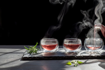 Still life book and a cup of tea on a wooden table,process brewing tea,Cup of freshly brewed fruit and herbal tea, darker background. .Hot water is poured from the kettle into a cup with tea.