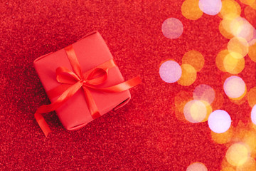 Christmas present in craft paper and red ribbon, on red bakground. Happy new year.